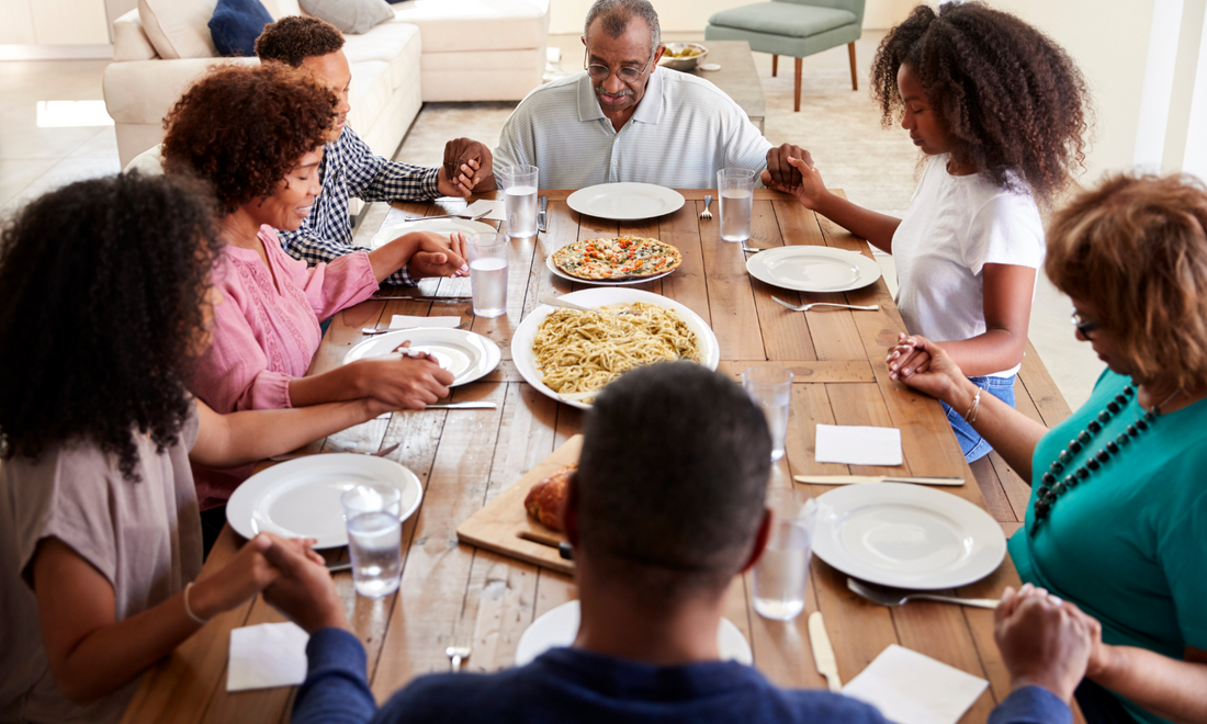 Family holding hands praying at dinner