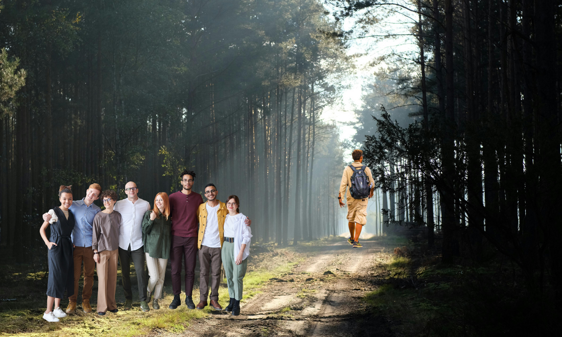 A person walking on a sunlit path away from a group,