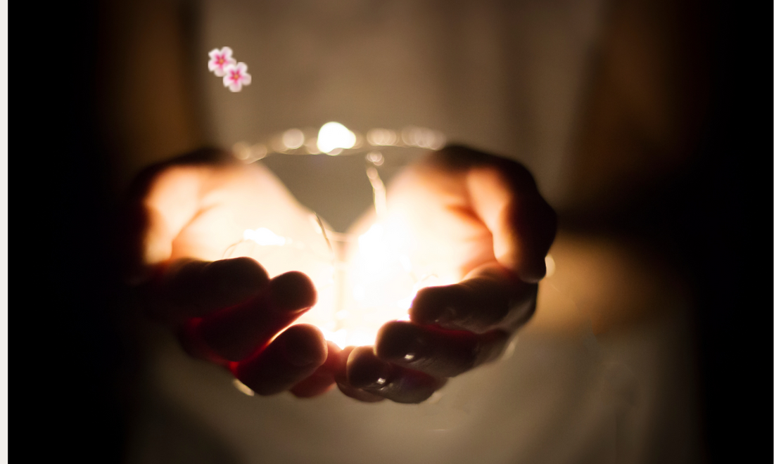A hand cupped around a small glowing light