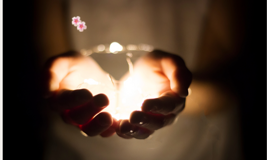 A hand cupped around a small glowing light