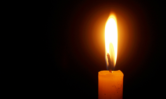 one single candle burning in the dark