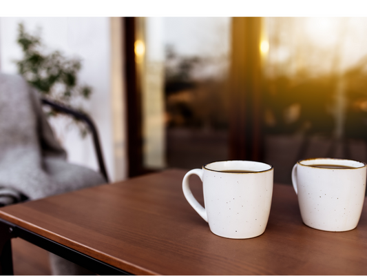 Two coffee cups on a table, one empty chair